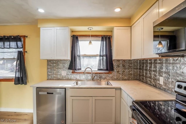 kitchen featuring pendant lighting, a sink, tasteful backsplash, appliances with stainless steel finishes, and baseboards