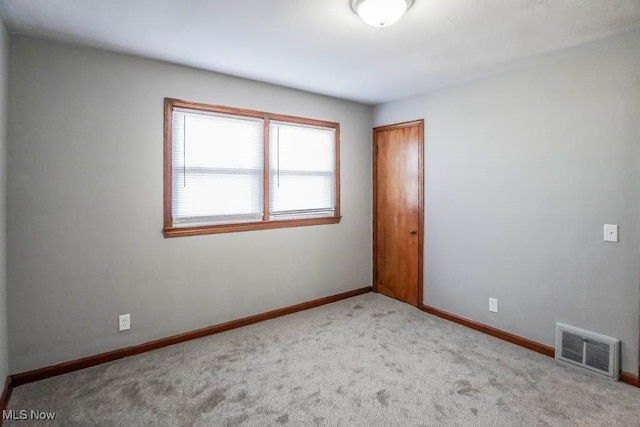 empty room featuring carpet, visible vents, and baseboards