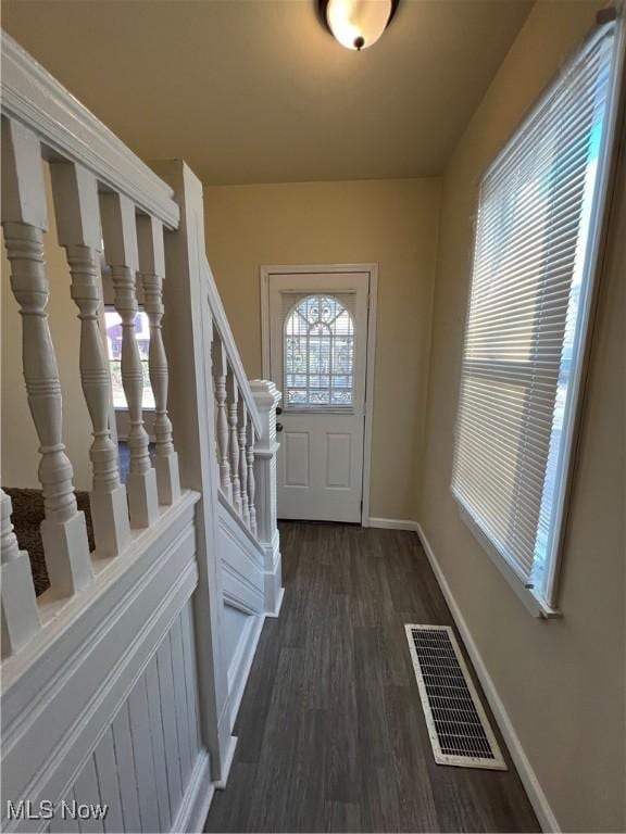 doorway featuring visible vents, baseboards, dark wood finished floors, and stairs