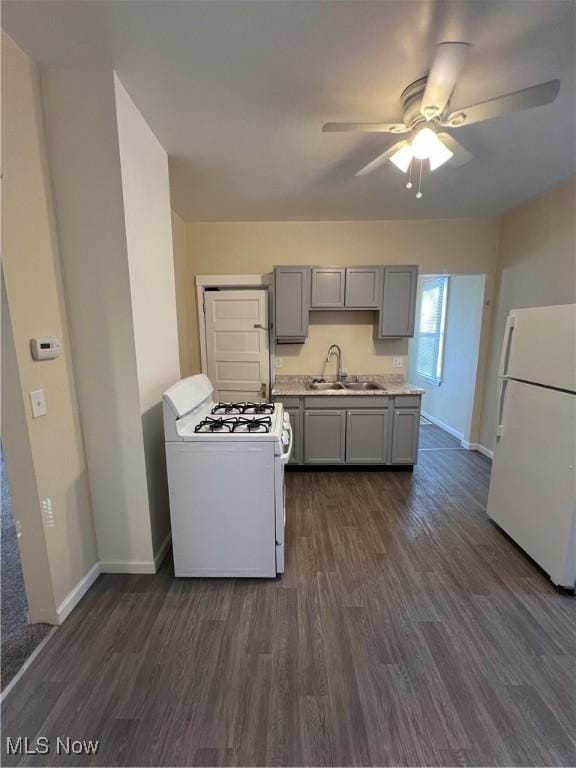 kitchen featuring dark wood-type flooring, gray cabinetry, a sink, white appliances, and light countertops