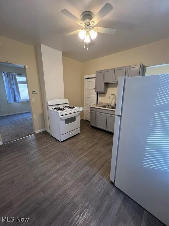 kitchen with gray cabinets, a sink, dark wood-style floors, white appliances, and ceiling fan