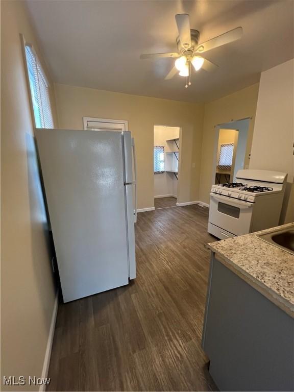 kitchen with white appliances, light countertops, dark wood-type flooring, and baseboards