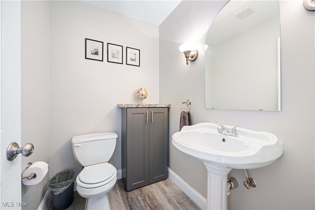 bathroom with visible vents, toilet, baseboards, and wood finished floors