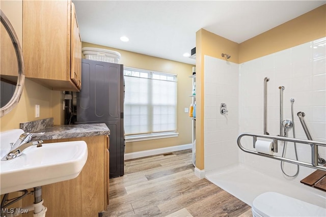 full bath featuring baseboards, toilet, a tile shower, recessed lighting, and wood finished floors