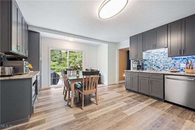 kitchen featuring decorative backsplash, stainless steel dishwasher, light wood-style flooring, and gray cabinets