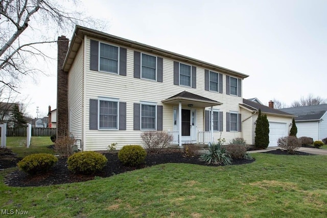 colonial inspired home featuring a garage, a chimney, and a front lawn