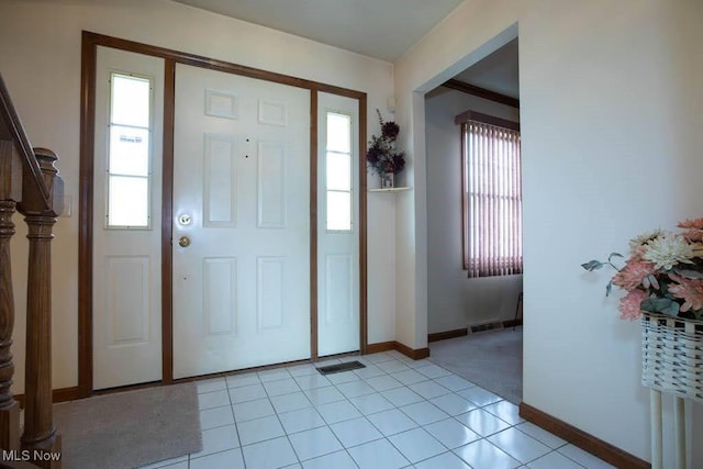 foyer entrance featuring light tile patterned floors, visible vents, and baseboards