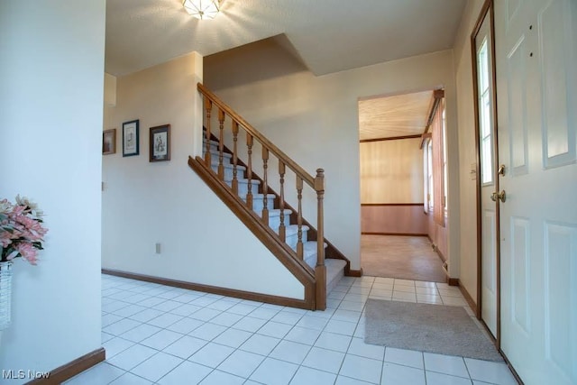 entryway with stairway, baseboards, and light tile patterned flooring