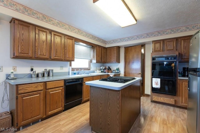 kitchen with a kitchen island, black appliances, light wood-style flooring, and brown cabinetry