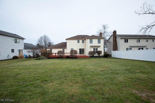 rear view of property with a wooden deck, a lawn, and fence