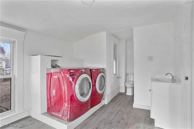 laundry room featuring baseboards, washer and clothes dryer, laundry area, wood finished floors, and a sink