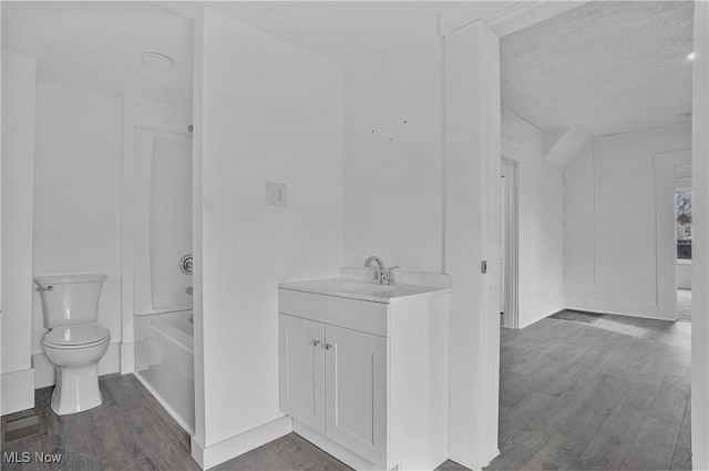 bathroom featuring washtub / shower combination, toilet, vanity, and wood finished floors