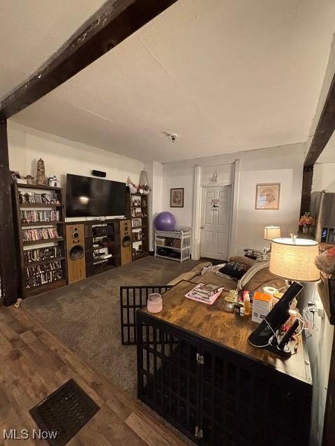 living area with beamed ceiling and wood finished floors