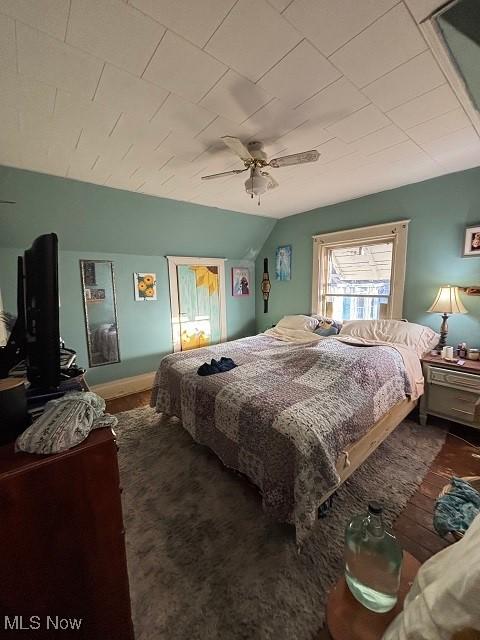 bedroom with ceiling fan, baseboards, and lofted ceiling