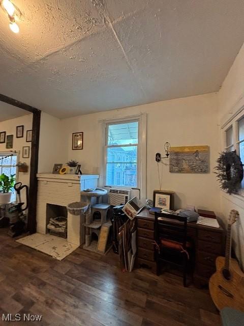 office area with a wealth of natural light, a brick fireplace, a textured ceiling, and wood finished floors