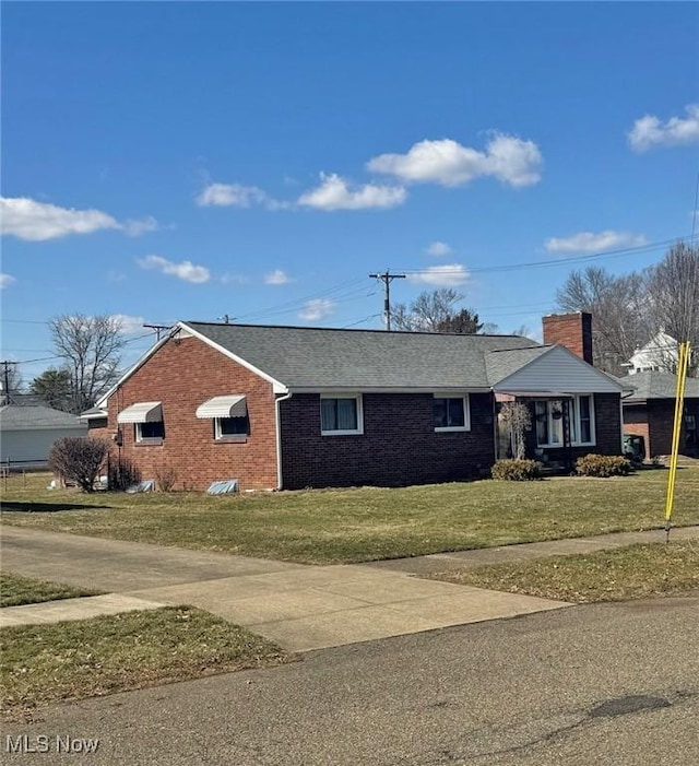 single story home featuring driveway, a front lawn, roof with shingles, brick siding, and a chimney