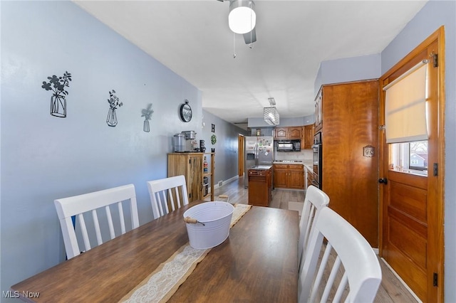 dining area with a ceiling fan and light wood-style floors