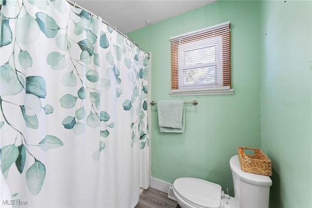 bathroom featuring a shower with shower curtain, baseboards, toilet, and wood finished floors