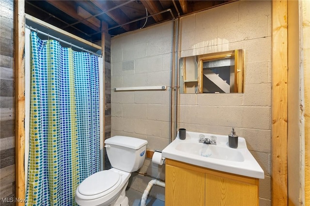 full bath featuring curtained shower, toilet, concrete block wall, and vanity