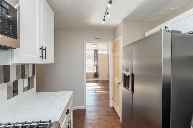 kitchen featuring a textured ceiling, backsplash, white cabinetry, stainless steel appliances, and dark wood-style flooring