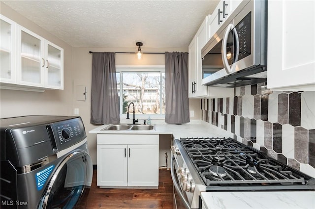 kitchen with a sink, stainless steel appliances, white cabinets, light countertops, and washer / dryer