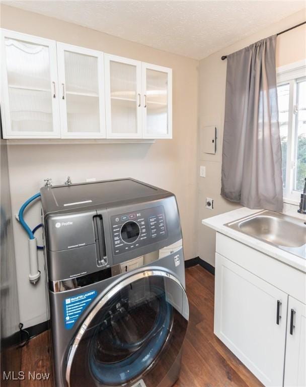 laundry area with a sink, a textured ceiling, dark wood finished floors, cabinet space, and washer / dryer