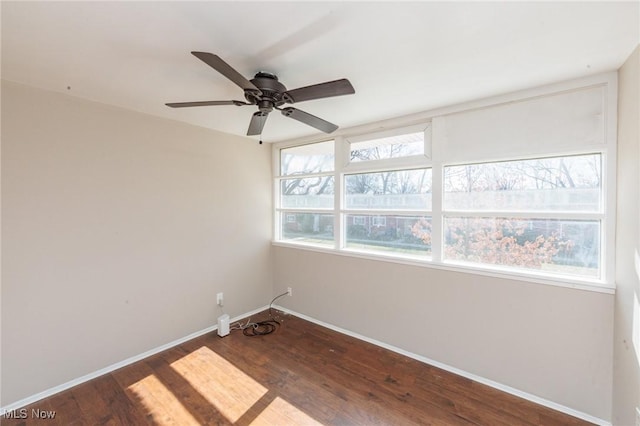 empty room with dark wood finished floors, plenty of natural light, and baseboards