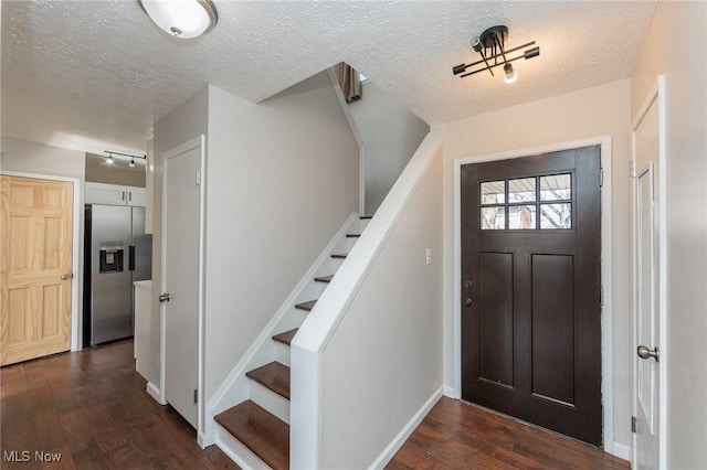 foyer featuring dark wood-type flooring, stairs, and a textured ceiling