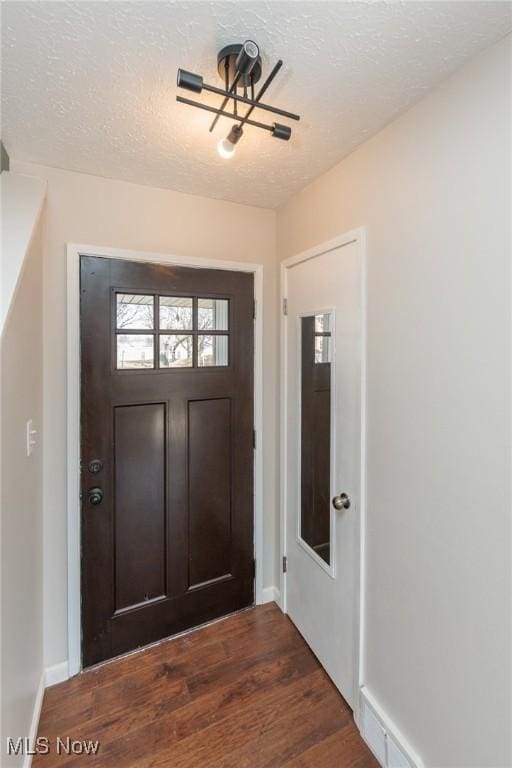 foyer entrance with baseboards, a textured ceiling, and dark wood-style flooring