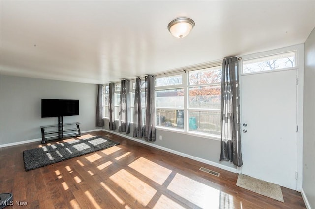 unfurnished living room with visible vents, baseboards, and wood finished floors