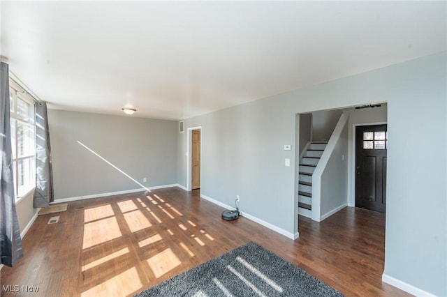 spare room with stairs, baseboards, and wood finished floors