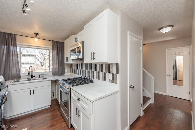 kitchen featuring a sink, appliances with stainless steel finishes, white cabinets, and dark wood-style flooring