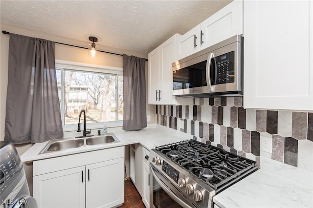 kitchen with backsplash, white cabinets, appliances with stainless steel finishes, and a sink