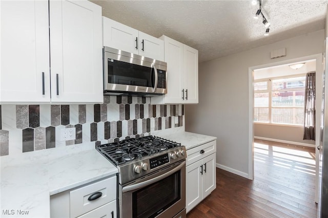 kitchen with tasteful backsplash, light stone countertops, appliances with stainless steel finishes, dark wood-style floors, and a textured ceiling