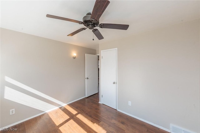 spare room with ceiling fan, wood finished floors, visible vents, and baseboards