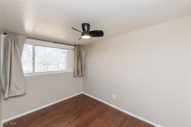 spare room featuring baseboards, dark wood-style flooring, and ceiling fan