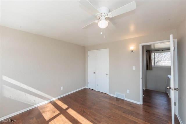 unfurnished bedroom featuring dark wood finished floors, baseboards, visible vents, and ceiling fan