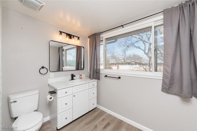 bathroom with toilet, vanity, baseboards, and wood finished floors