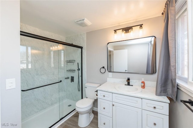 bathroom with visible vents, a stall shower, toilet, and vanity