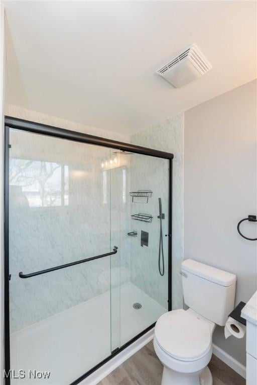 bathroom featuring visible vents, toilet, a stall shower, wood finished floors, and vanity