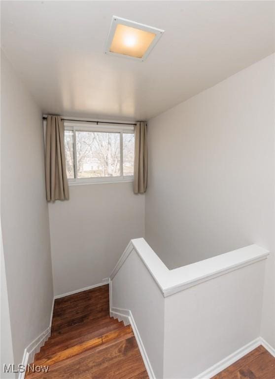 staircase featuring baseboards and wood finished floors