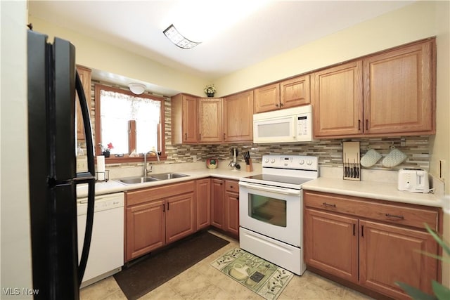 kitchen with decorative backsplash, white appliances, light countertops, and a sink