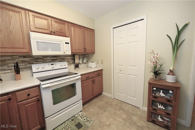 kitchen with tasteful backsplash, white appliances, light countertops, and baseboards