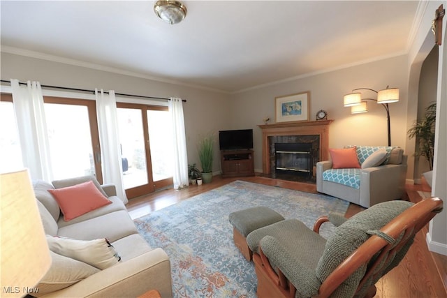 living room with a high end fireplace, crown molding, baseboards, and wood finished floors