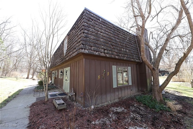 view of side of home with mansard roof and board and batten siding