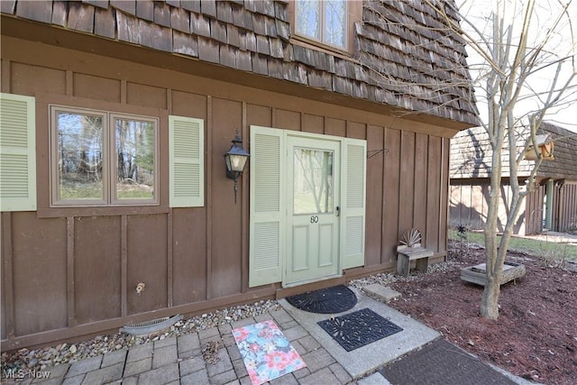 doorway to property featuring board and batten siding and mansard roof