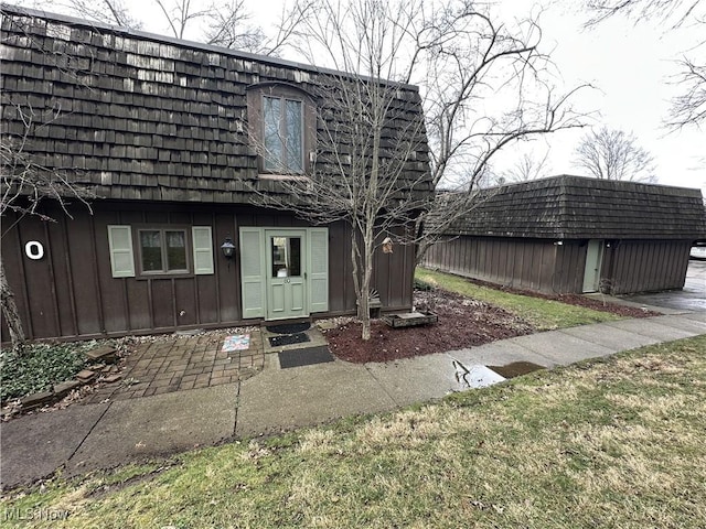 exterior space with an outbuilding, mansard roof, and board and batten siding