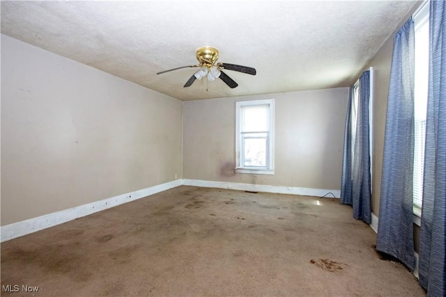 empty room with a textured ceiling, a ceiling fan, baseboards, and carpet floors