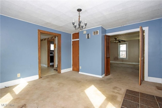 carpeted spare room featuring visible vents, ceiling fan with notable chandelier, and baseboards