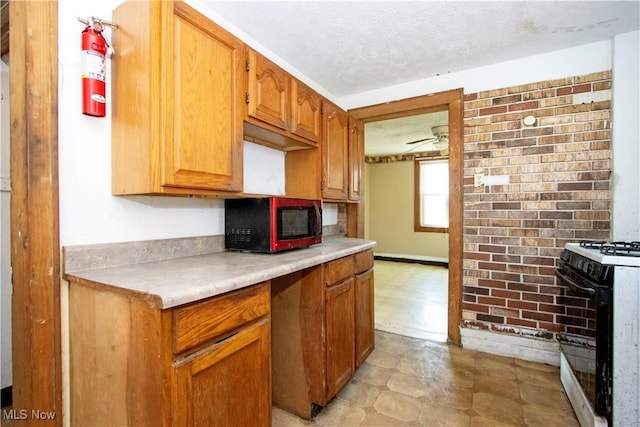 kitchen featuring range with gas cooktop, light floors, light countertops, a textured ceiling, and a ceiling fan